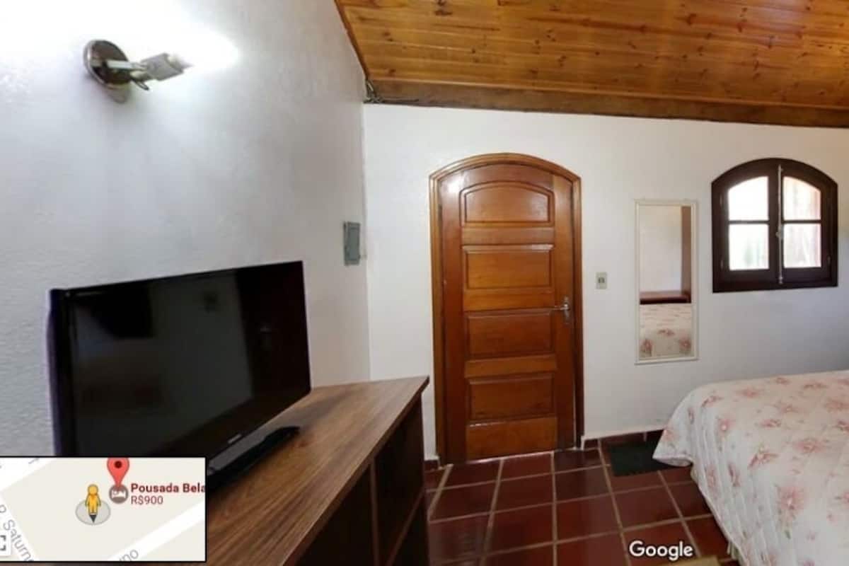 Ein Schlafzimmer mit Bett, Fernseher, Holztür und Fenster.