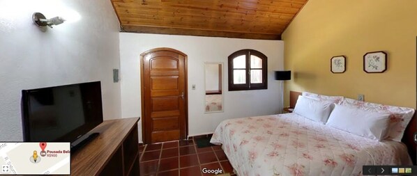 A bedroom with a bed, a television, a wooden door, and a window. - POUSADA BELA VISTA (Camanducaia)