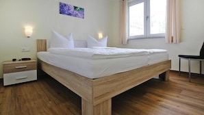 A modern bedroom with a wooden bed, bedside tables, and a window with curtains.