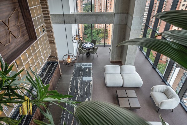 Un intérieur moderne situé dans un immeuble de grande hauteur, comprenant un espace repas, des sièges et de grandes fenêtres offrant une vue sur la ville.