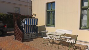 Un espace extérieur aménagé avec une table et des chaises, un banc abrité et un portail en bois.