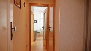 Un couloir étroit avec des portes en bois et un plancher de couleur claire.