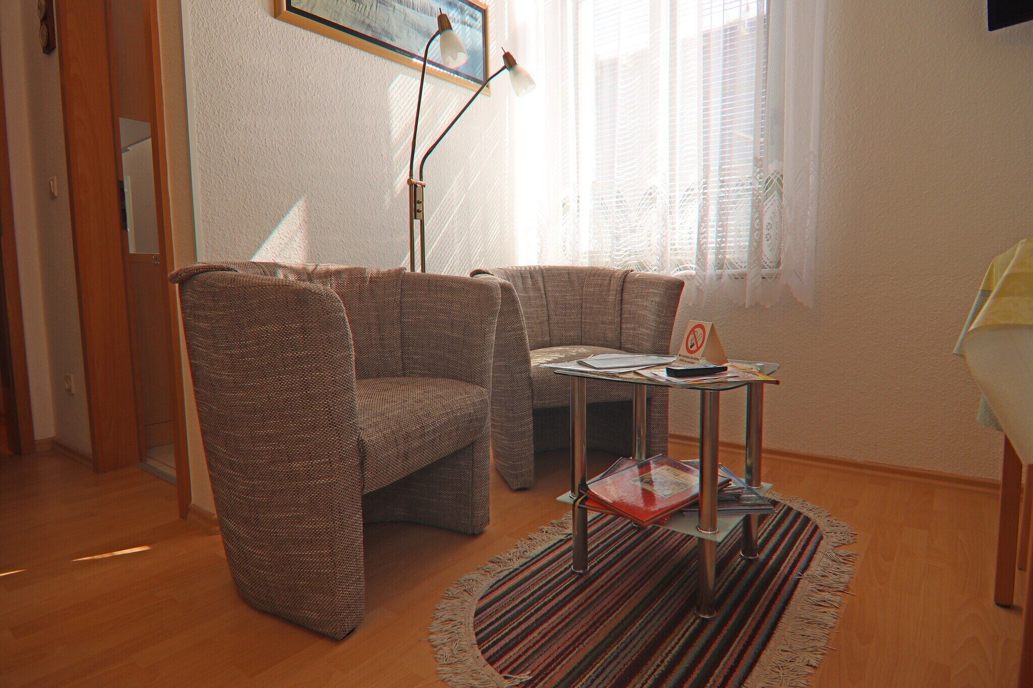 A cozy living room with two brown armchairs, a small table with a lamp, and a patterned rug.