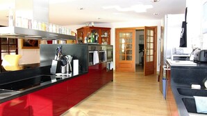 Una cocina moderna con armarios rojos, electrodomésticos de acero inoxidable y un rincón comedor de madera.
