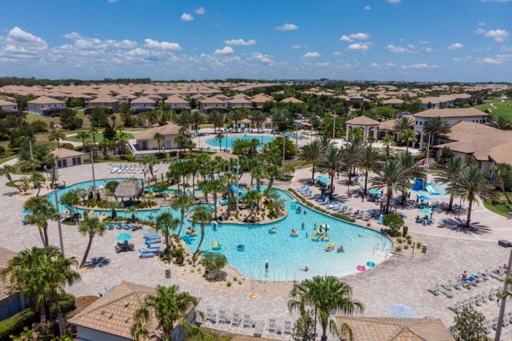A resort with multiple swimming pools, palm trees, and a clear blue sky.