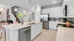 A modern kitchen with white cabinets, stainless steel appliances, and pendant lighting. - Last Minute Disney! Private Pool, Hot Tub, Game Room & Themed Bedrooms. Book Now! #65867 (Orlando)