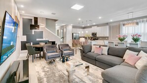 A modern living room with a sofa, chairs, a coffee table, and a TV. - Last Minute Disney! Private Pool, Hot Tub, Game Room & Themed Bedrooms. Book Now! #65867 (Orlando)