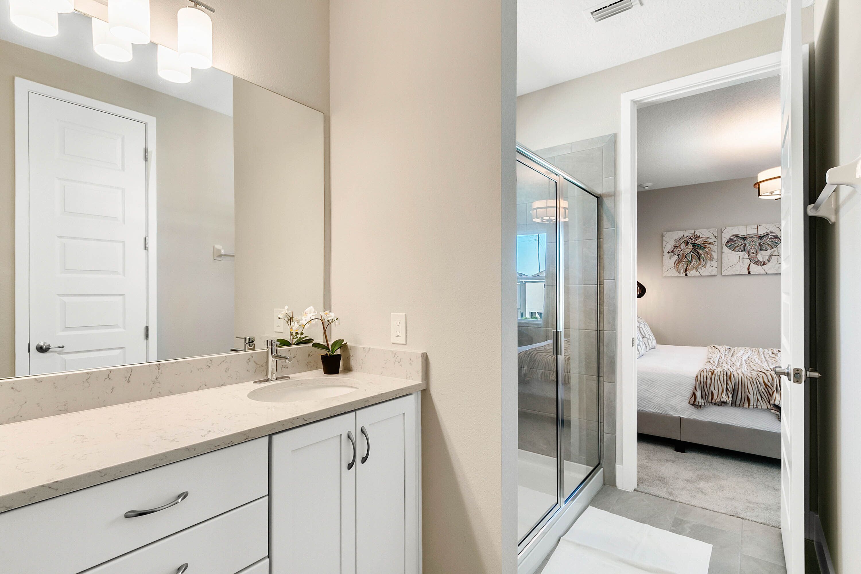 Un baño moderno con encimera de mármol, un espejo grande y cabina de ducha de vidrio.