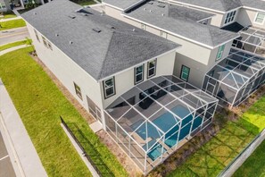 Une maison moderne à deux étages dotée d’un grand espace piscine entièrement vitré.
