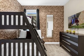 Une chambre avec un lit superposé, une commode, un miroir et un tableau accroché au mur.