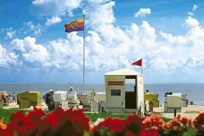 A beach with a lifeguard station, a flag, and a clear sky.