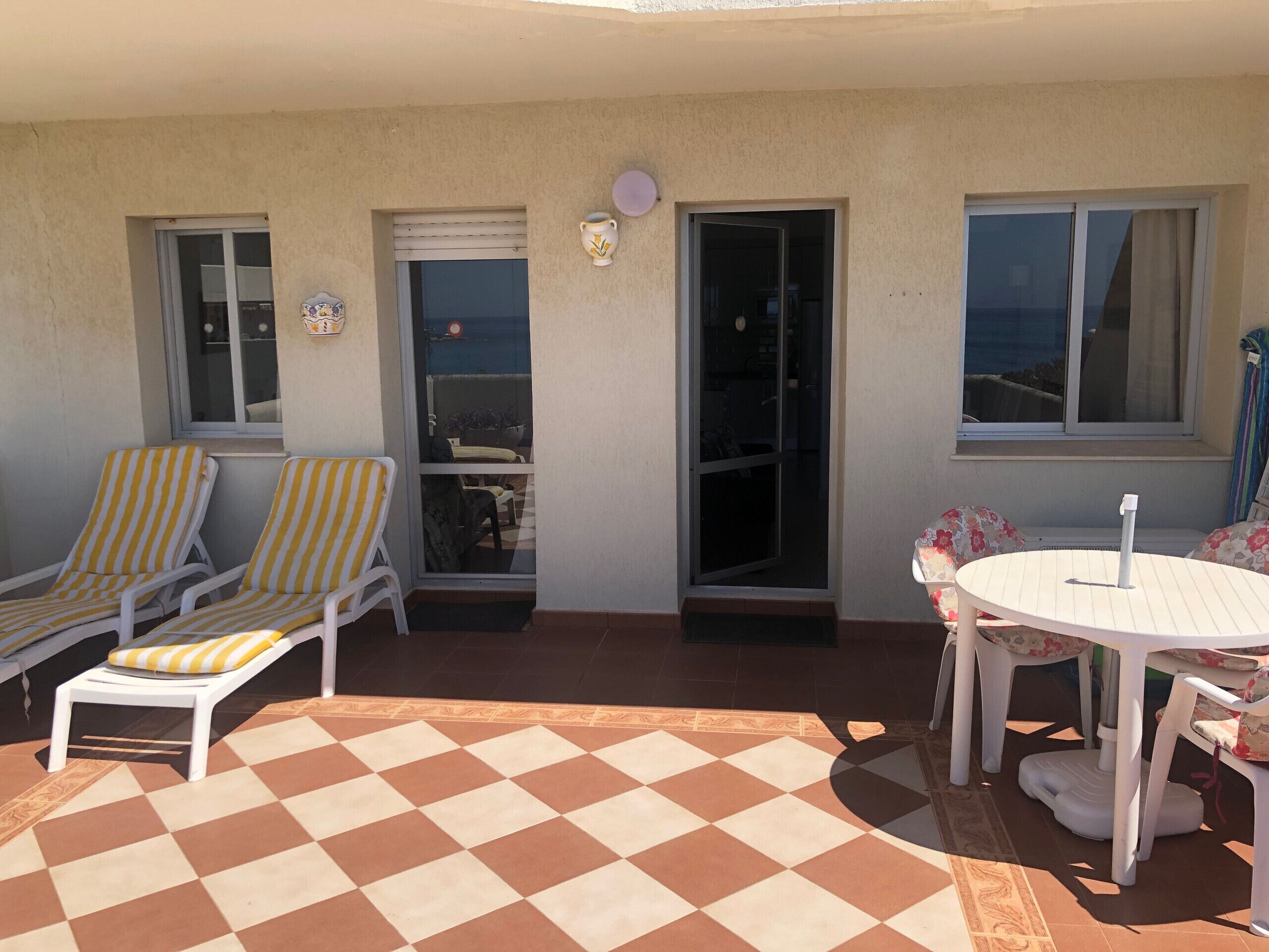 Un espace extérieur abrité comprenant deux chaises longues, une petite table et un sol à motifs.