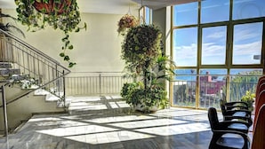 Un vaste espace intérieur doté d’un sol en marbre, d’un escalier et de grandes fenêtres offrant une vue sur la ville.