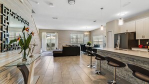 A modern kitchen with a central island, bar stools, and a dining area with a glass partition. - Last Minute Disney Getaway! Townhouse with Private Pool. Book Now! #65787 (Orlando)