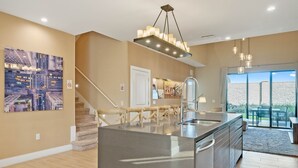 A modern kitchen with a central island, a staircase, and a large window with a view. - Last Minute Disney Getaway! Luxury Villa with Private Pool. Book Now! #66003 (Orlando)