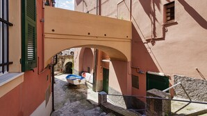 Uma estreita viela com uma ponte de pedra, barcos e um edifício com venezianas verdes.