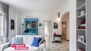 Uma sala de estar com um sofá branco, um armário azul e uma estante.