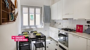 Cozinha moderna com armários brancos, fogão a gás e mesa de jantar posta com pratos e copos.