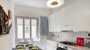 A modern kitchen with white cabinets, a gas stove, and a dining table set with plates and glasses.