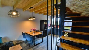 A modern interior with a dining area, wooden staircase, and a kitchen in the background. - Large, 2-story holiday home, sauna, jacuzzi (Mielenko)