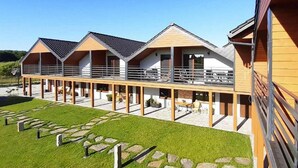 A row of wooden cabins with balconies, arranged in a linear fashion along a paved walkway. - Large, 2-story holiday home, sauna, jacuzzi (Mielenko)