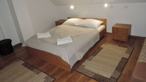 A neatly made bed with a wooden headboard, two bedside tables, and a small black stool.