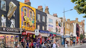 Una calle con comercios, incluyendo una zapatería y un edificio colorido con un gran mural de un elefante.