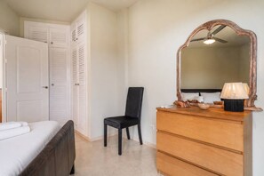 Ein Schlafzimmer mit Bett, Stuhl, Kommode und Spiegel.