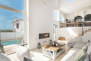 Ein großzügiges Wohnzimmer mit Pool, Treppe und Balkon.