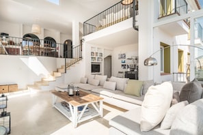 A spacious living area with a staircase, a sofa set, a coffee table, and a bookshelf.