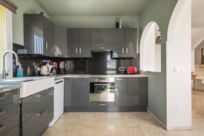 Eine moderne Küche mit dunklen Schränken, einem Edelstahlbackofen und einem roten Toaster.