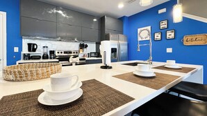 Une cuisine moderne dotée d’un îlot central, d’appareils électroménagers en acier inoxydable et d’un mur d’accent bleu.