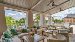 An outdoor patio with beige sofas, wicker chairs, and a wooden table.