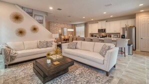 A modern living room with two sofas, a coffee table, and a kitchen in the background.