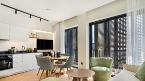 Un apartamento moderno con cocina, comedor y sala de estar con sofá y sillones.