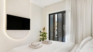 Una habitación de hotel moderna con una cama grande, un televisor de pantalla plana montado en la pared y un divisor corredero decorativo.