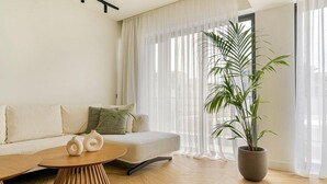 Ein modernes Wohnzimmer mit einer Couch, einem runden Holztisch und einer großen Topfpflanze.