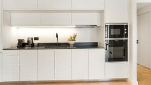 Eine moderne Küche mit weißen Schränken, einer schwarzen Arbeitsplatte, einer Edelstahlspüle, einem Bosch-Backofen und einer Obstschale auf der Theke.