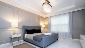 A modern bedroom with a large bed, bedside lamps, a chandelier, and a view of the outdoors. - Breathtaking Home Private Pool Game Room 1725 (Kissimmee)