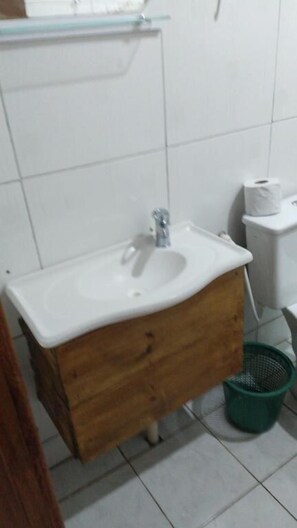A bathroom with a white sink, wooden cabinet, and a green basket. - Pousada Avenida (Urubici)