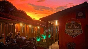 Un edificio con un cartello che riporta "Pousada Avenida" e uno scooter parcheggiato davanti.
