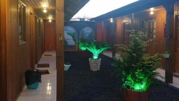 Un corridoio coperto con pareti in legno e pavimento piastrellato, che conduce a un edificio con diverse porte.