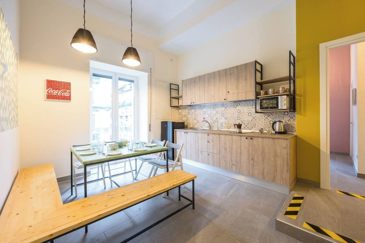 A modern kitchen with wooden cabinets, a dining table with chairs, and a bench.