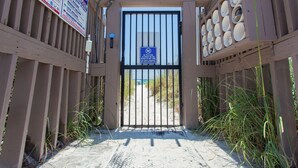 A beach gate with a no pets sign, wooden fence, and beach access path.