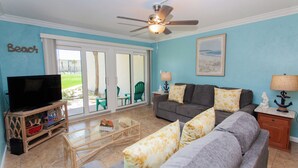 A living room with a television, a sofa, a coffee table, and a ceiling fan.