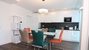 A modern kitchen with white cabinets, a black microwave, and a dining area with a table and chairs.