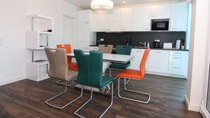 A modern kitchen with white cabinets, a black microwave, and a dining area with a table and chairs.