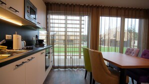 A modern kitchen with a dining area, large windows, and a view of a green landscape. - Chalet in Wendorf (Wendorf)