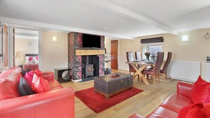 A spacious living room with a fireplace, a dining area, and a red leather sofa.