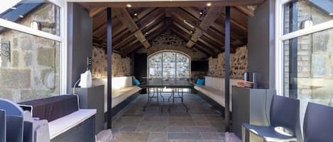 Un espace extérieur abrité, avec des murs en pierre, une table et des chaises.